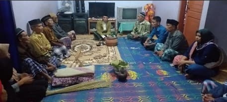 Warga berkumpul duduk melingkar di dalam rumah pada upacara ruwatan boyongan di Sinom